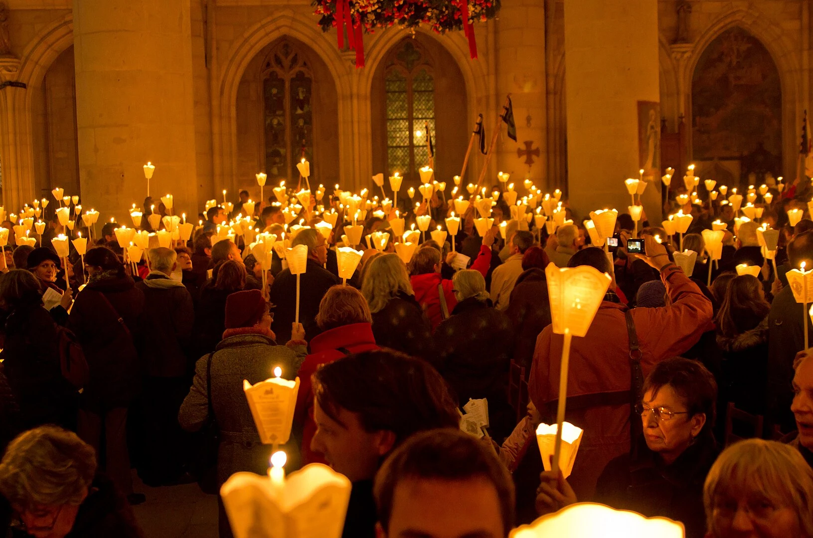 Procession aux cierges dans la basilique de Saint-Nicolas-de-Port, lumière chaleureuse et ferveur populaire, photo publiée par monsieurdefrance.com.