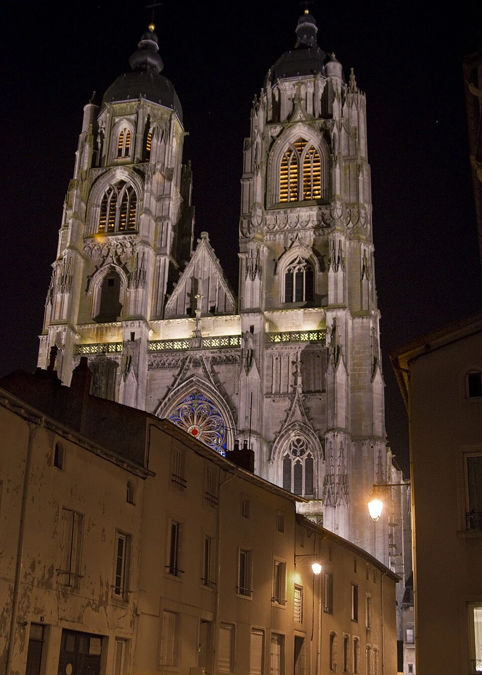 Façade nocturne de la basilique de Saint-Nicolas-de-Port, illuminée avec ses deux clochers à bulbe, photo publiée par monsieurdefrance.com.