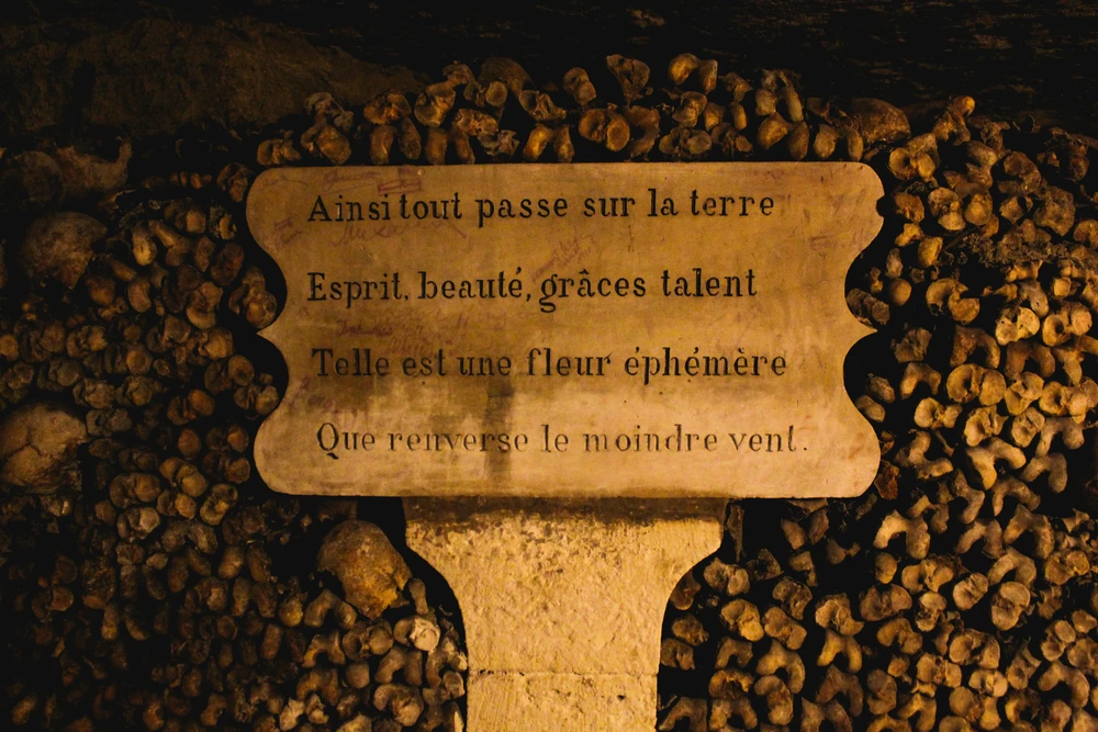 Un panneau de méditation dans les catacombes de Paris invite au recueillement et à la réflexion sur la mort et le temps qui passe, renforçant l’atmosphère solennelle et spirituelle de ce lieu unique sous la capitale, photo choisie par monsieurdefrance.com.