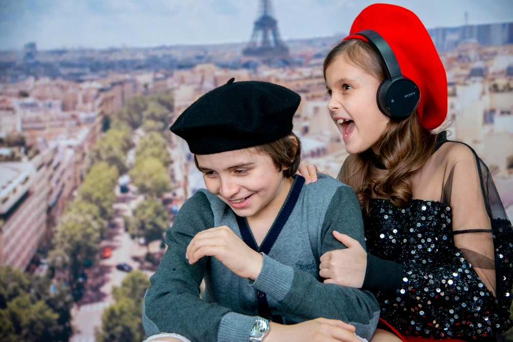 Two children wearing berets playfully enjoying clichés about the French, light-hearted and humorous scene, photo chosen by monsieurdefrance.com.
