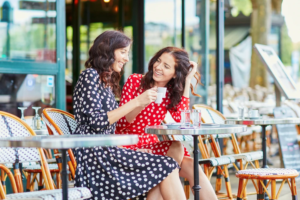 Deux femmes amies en terrasse d’un café parisien, moment convivial et typiquement français, photo choisie par monsieurdefrance.com.