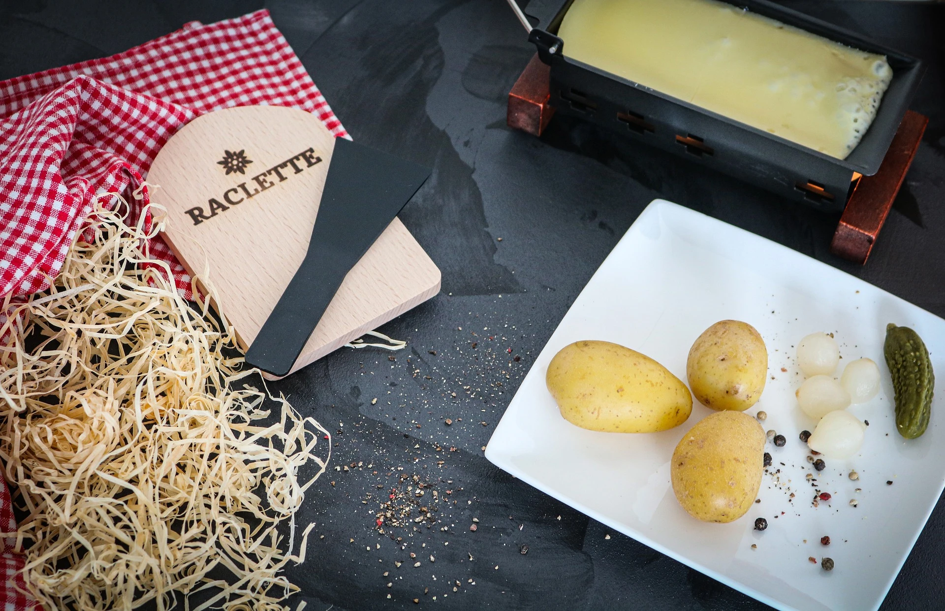 Zutaten für ein Raclette: Schmelzkäse, Wurstwaren und Kartoffeln für ein geselliges Winteressen in Frankreich.