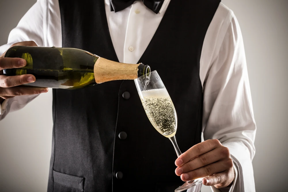 C'est comme cela qu'on sert un champagne : tenir la bouteille par le culot et incliner le verre pour faire moins mousser ... Photo choisie par Monsieurdefrance.fr : Minerva Studio/Shutterstock.fr