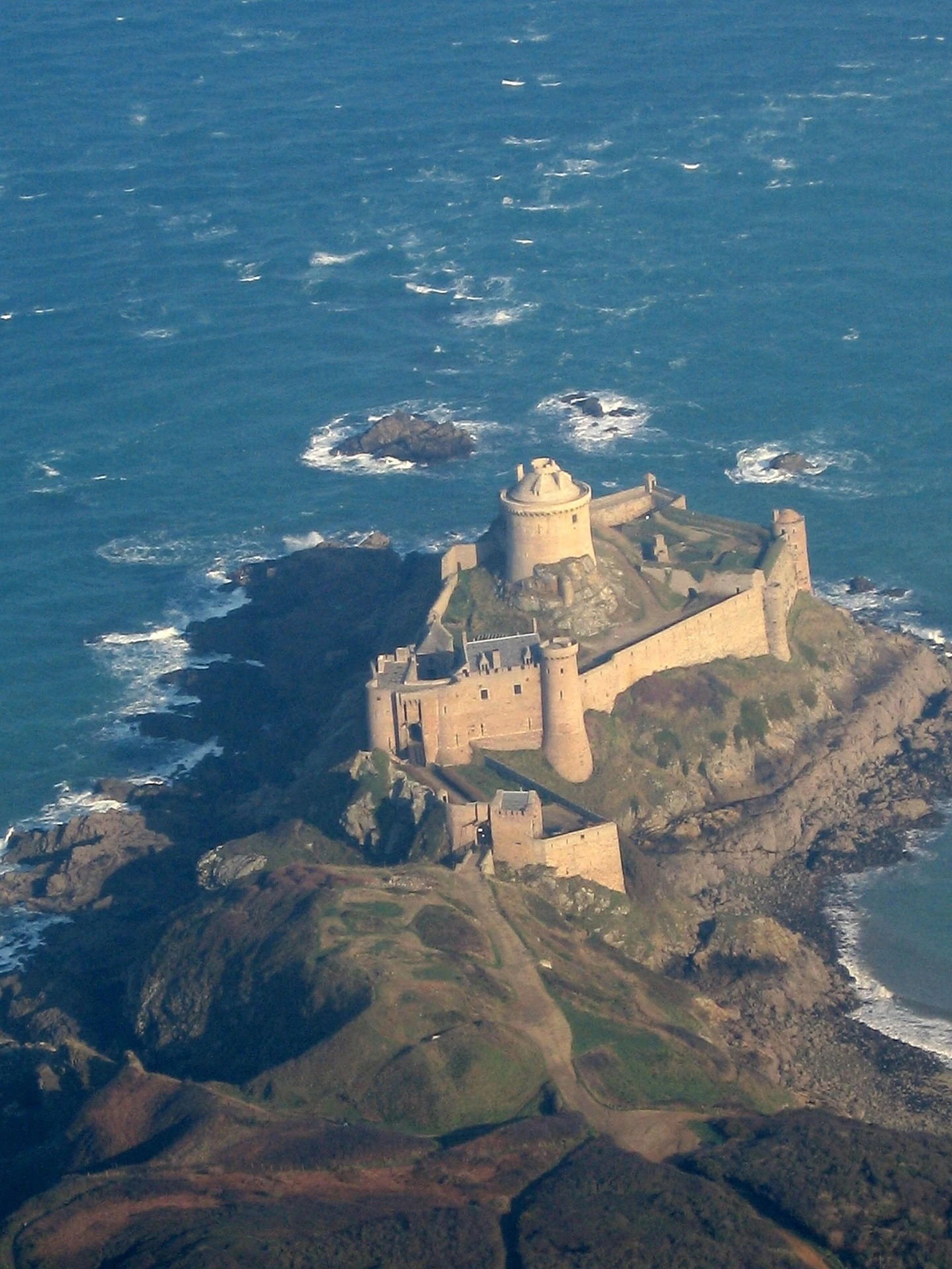 Fort La Latte in the middle of the waves, an iconic fortified castle on the Emerald Coast perched on a promontory facing the sea, one of the must-see sights near Cap Fréhel. Photo chosen by monsieur-de-france.com: by Gwenaële Moignic from Pixabay.