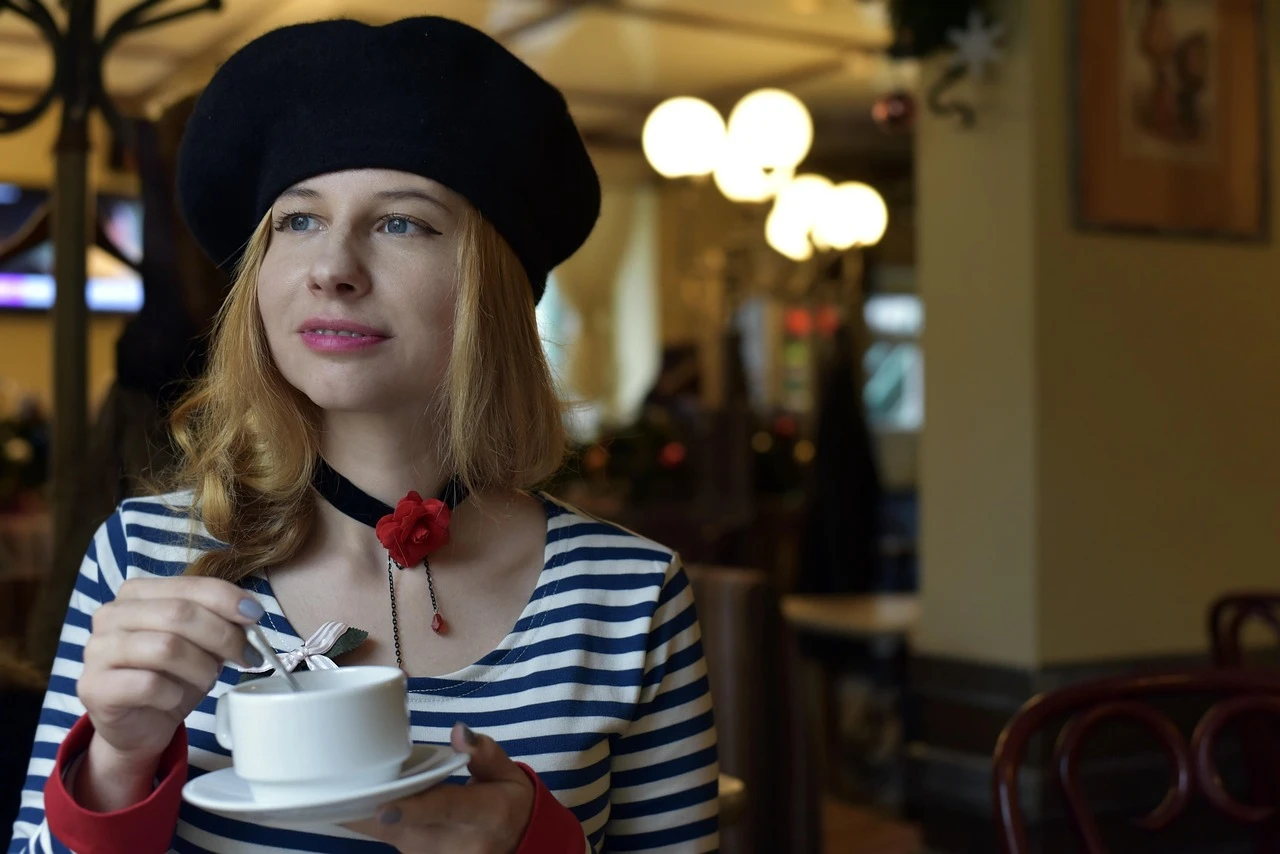 A typical cliché: a young girl in a striped shirt and Basque beret drinking coffee in Paris, a playful fantasy of French stereotypes, photo chosen by monsieurdefrance.com.